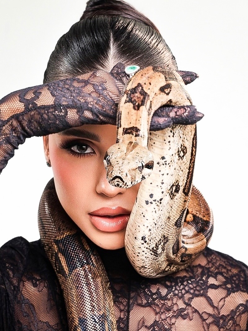 Woman in lace holding patterned snake near face against white background